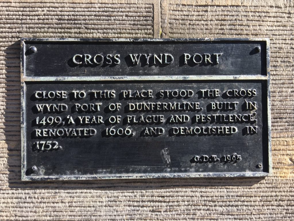 Plaque with writing "Cross Wynd Port. Close to this place stood the Cross Wynd port of Dunfermline built in 1499, 'a year of plague and pestilence' renovated in 1606, and demolished in 1752."
